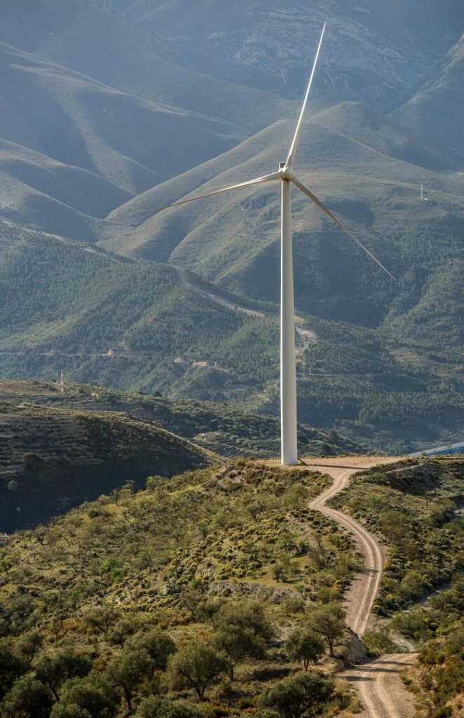 A solitary wind turbine stands amidst a rugged mountain landscape, harnessing renewable energy.